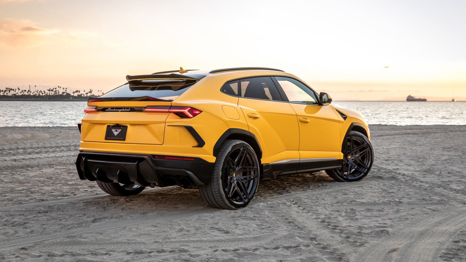 Желтый автомобиль  Lamborghini Urus на песке у моря