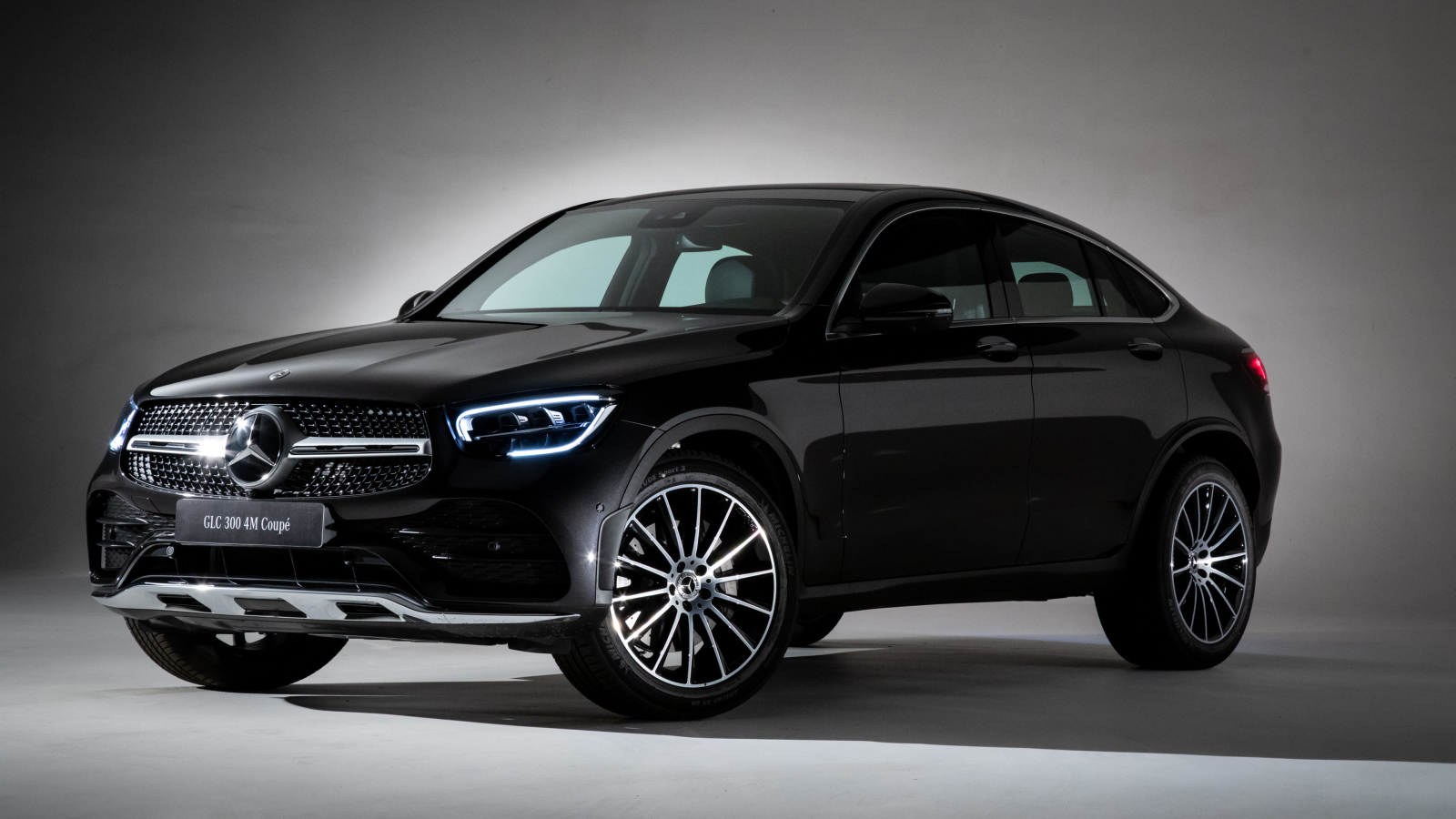 Черный стильный автомобиль Mercedes-Benz GLC 300,  2019 года на сером фоне