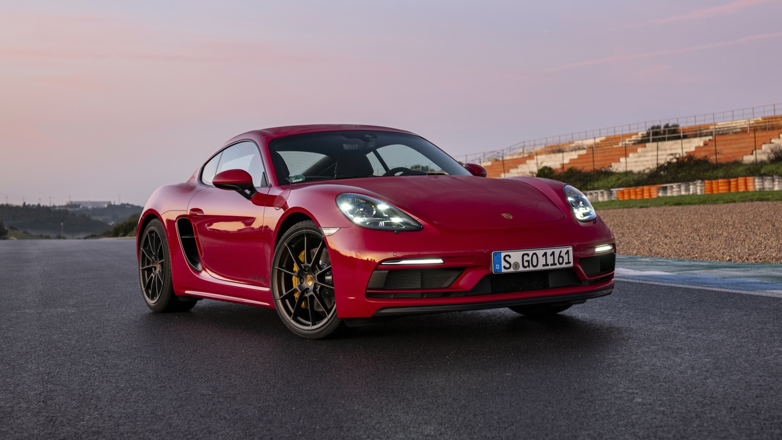 Красный автомобиль Porsche 718 Cayman GTS 4,  2020  года на стадионе