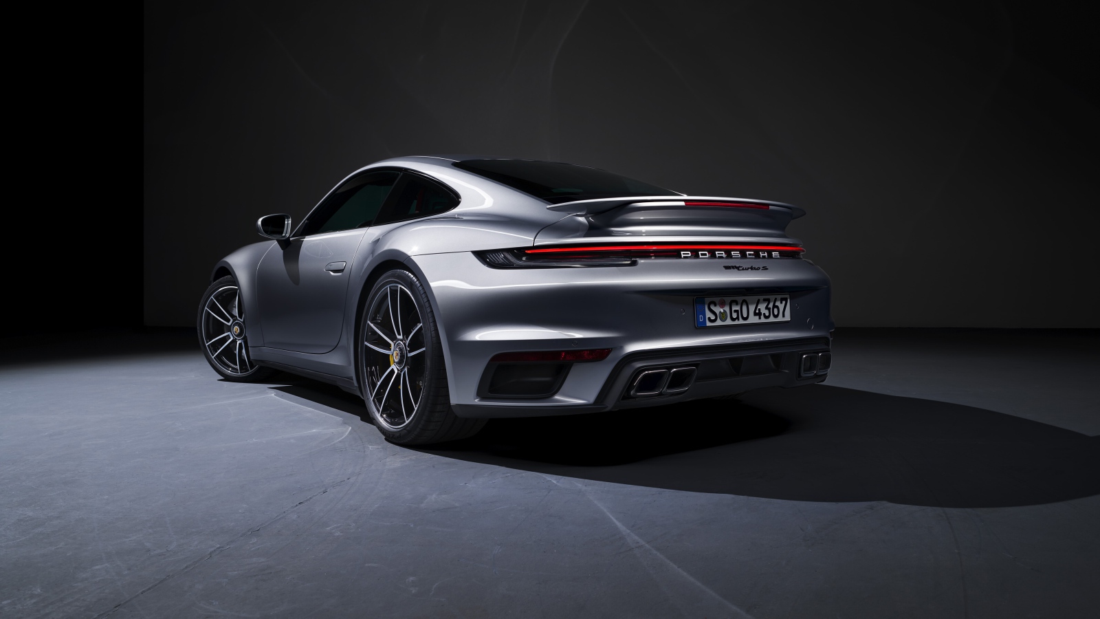 Серебристый автомобиль Porsche 911 Turbo S 2020 года вид сзади