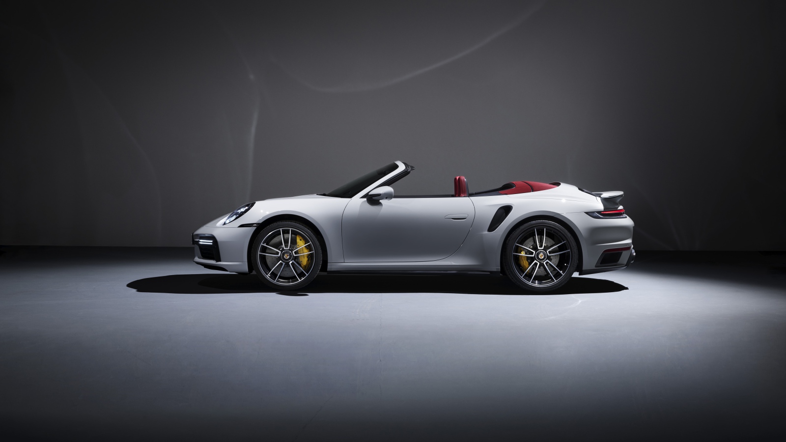 Белый автомобиль Porsche 911 Turbo S Cabriolet 2020 года на сером фоне