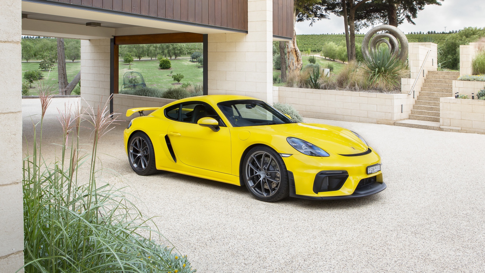 Желтый автомобиль Porsche 718 Cayman GT4, 2020 года у дома