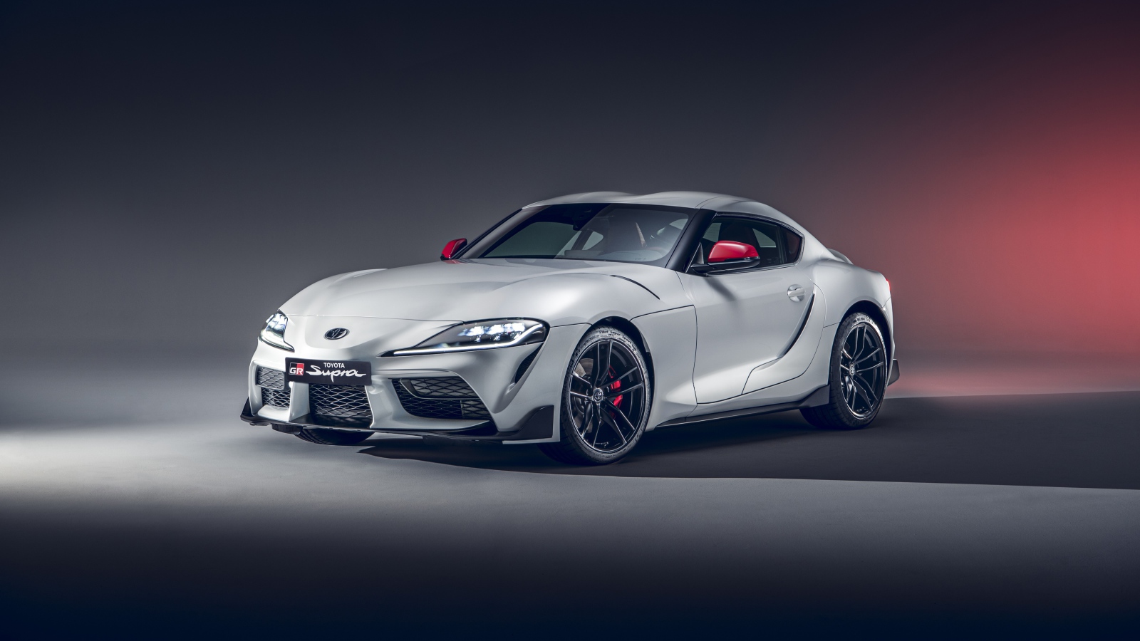 Серебристый автомобиль Toyota GR Supra 2L 2020 года на сером фоне