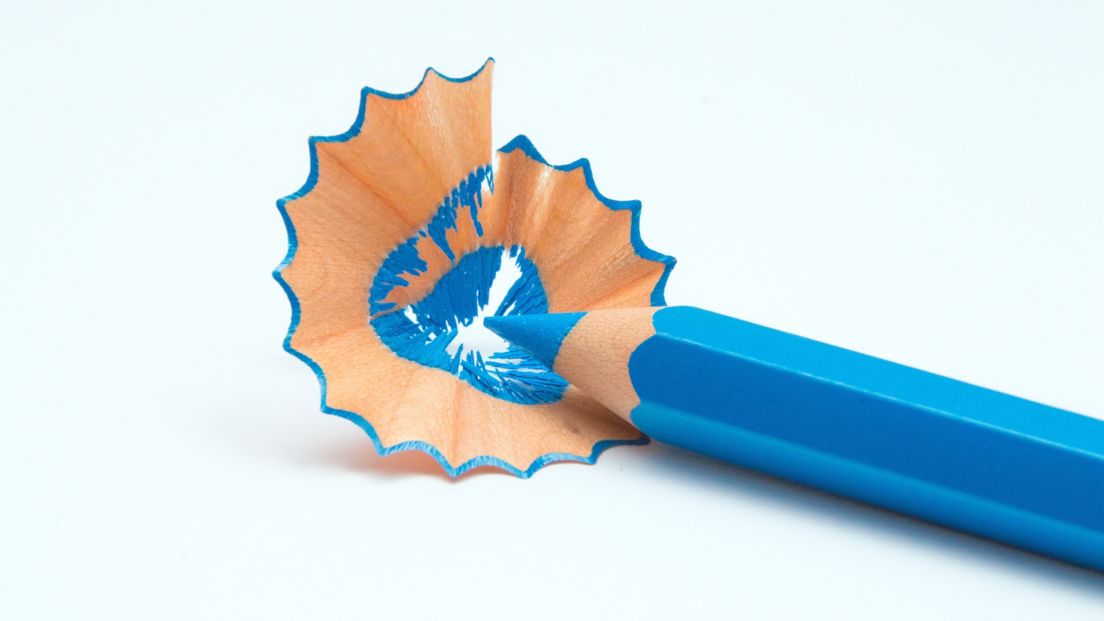 Голубой карандаш со стружкой на белом фоне