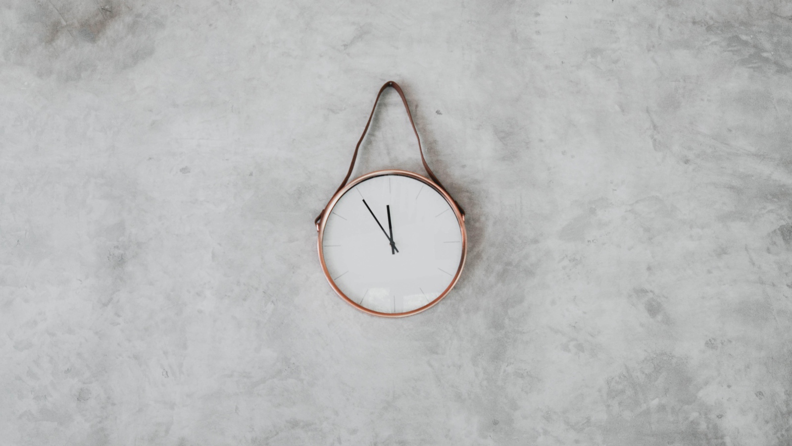 Clock with black arrows hang on a gray wall