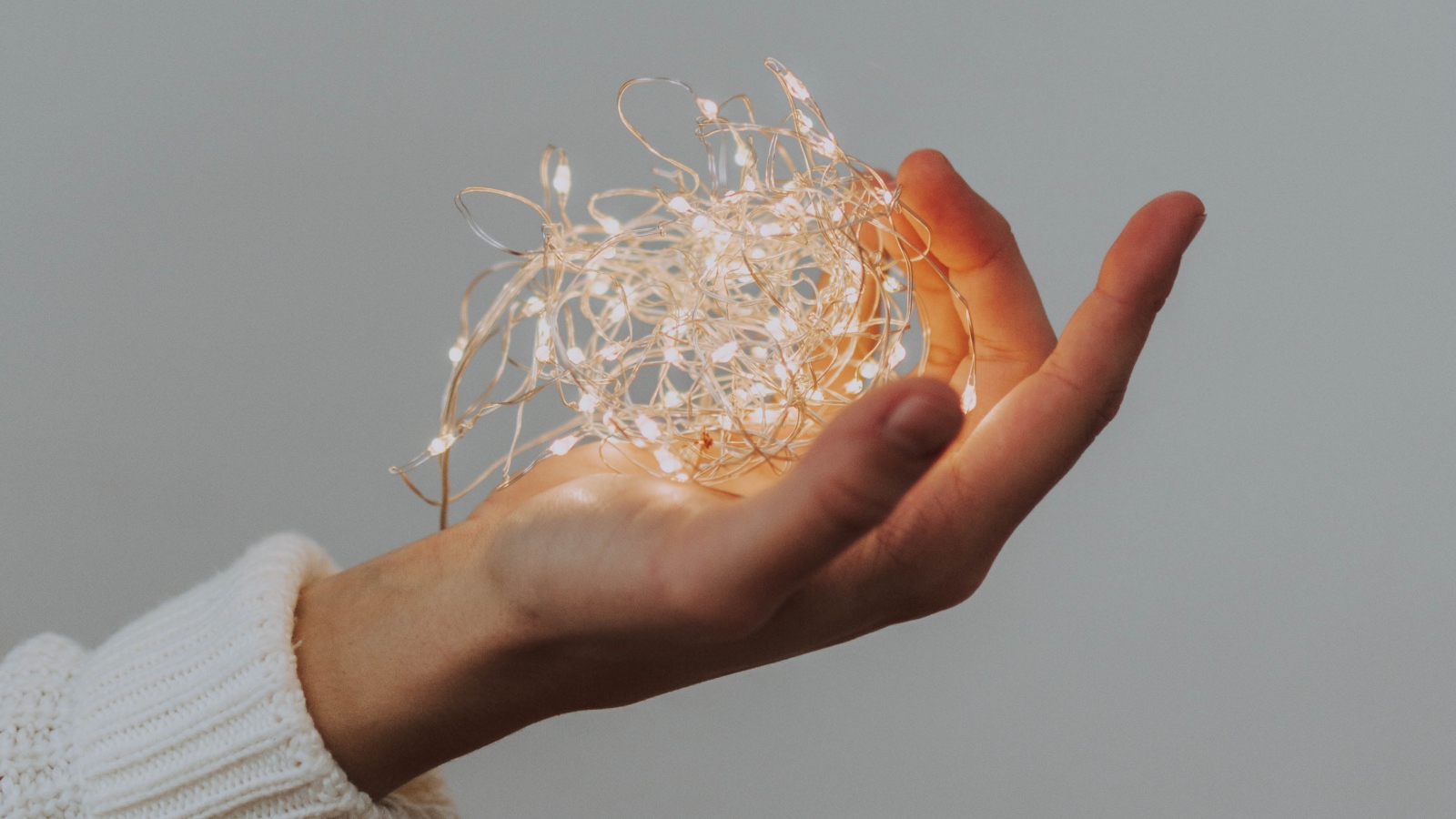 Включенная гирлянда в руке на сером фоне