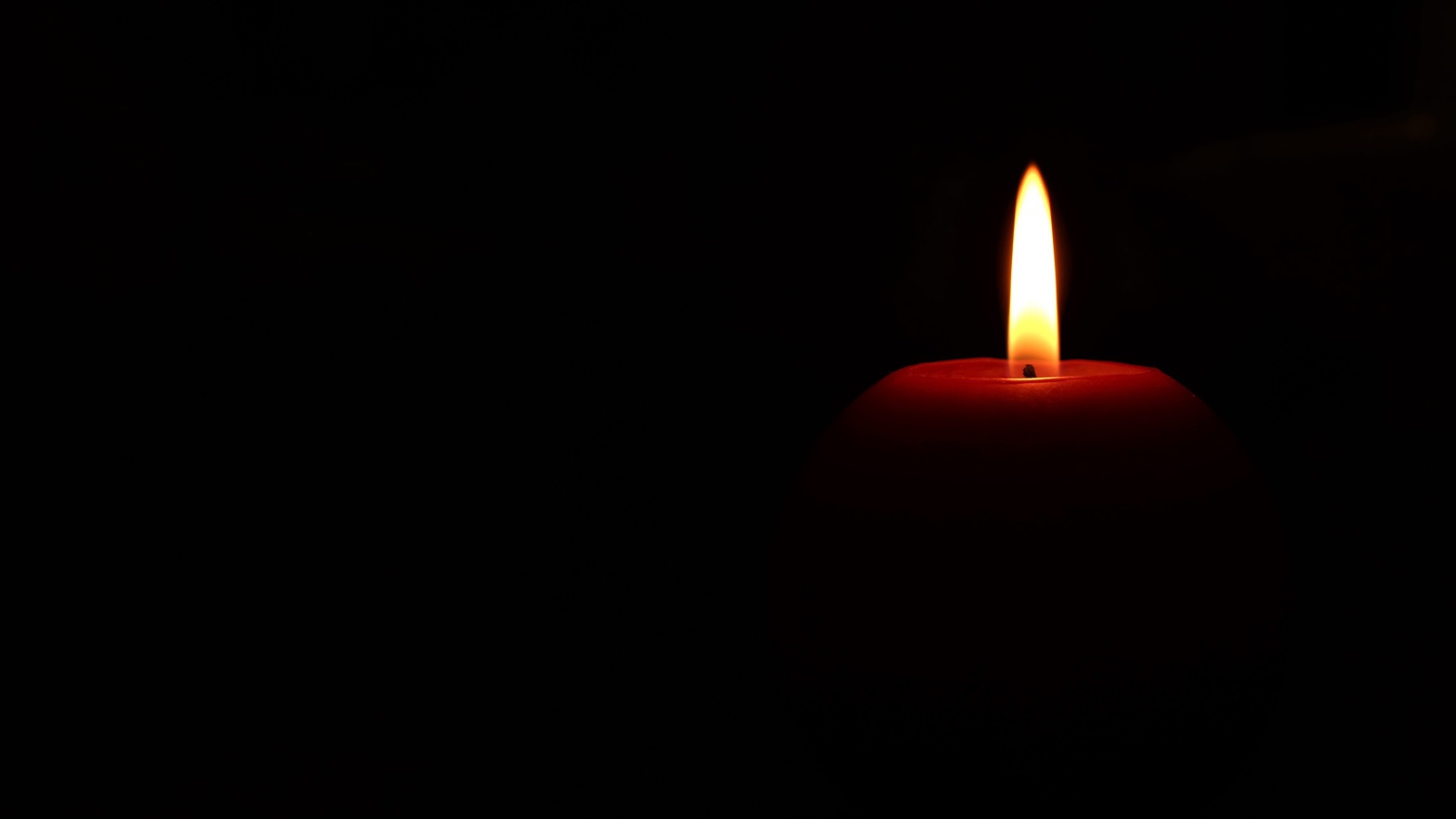 Зажженная красная свеча на черном фоне