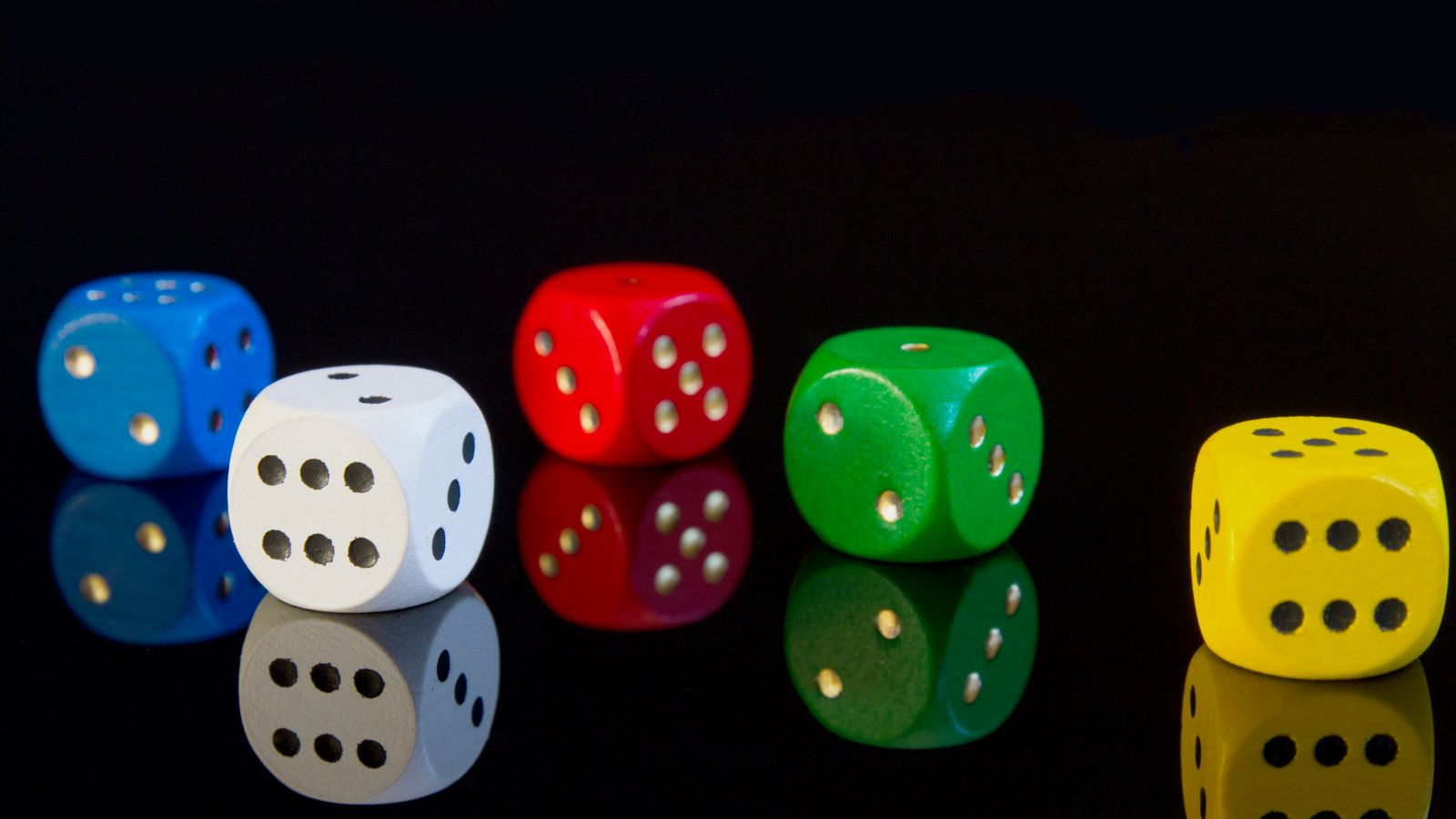 Разноцветные игральные кубики на черном фоне
