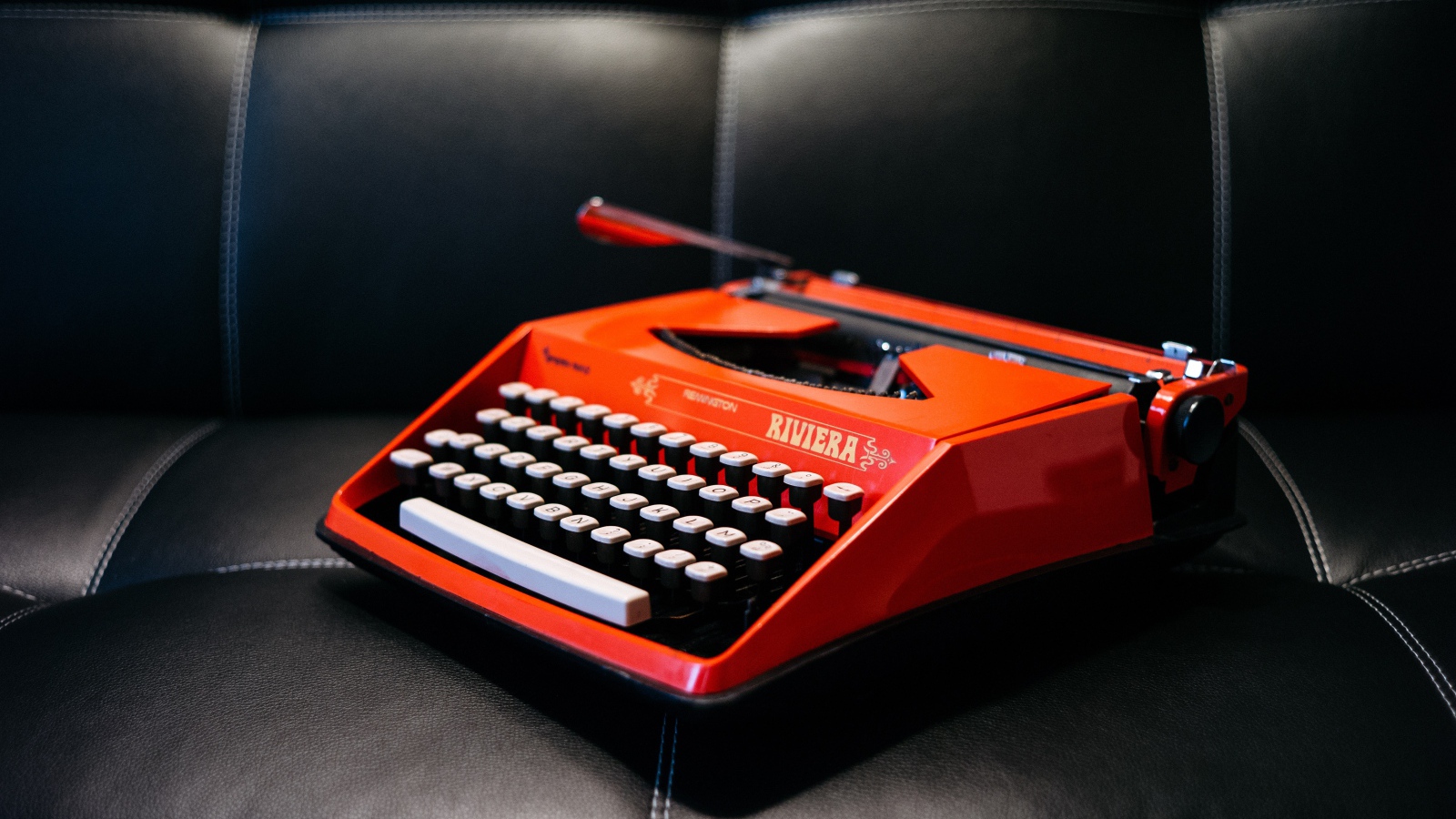 Старая красная печатная машинка на черном диване