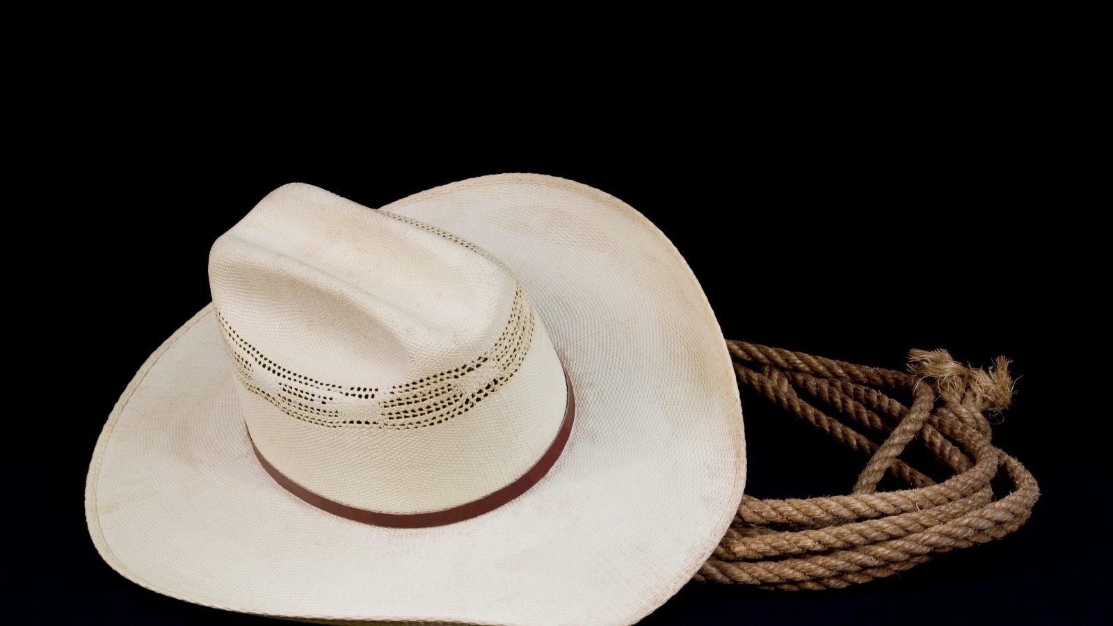Белая ковбойская шляпа с лассо на черном фоне