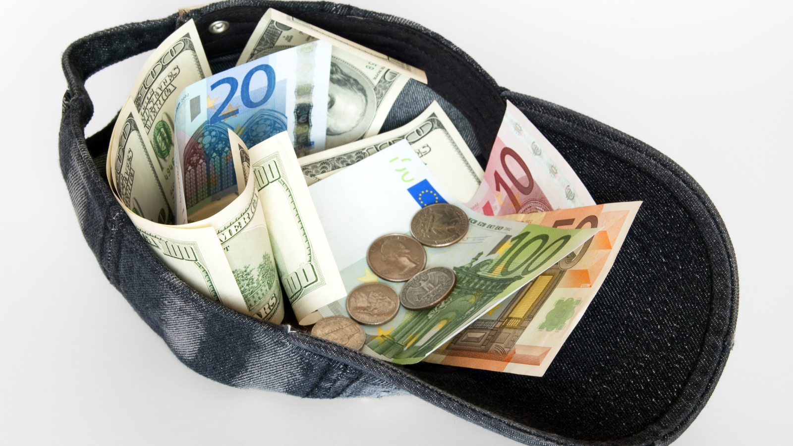 Бейсболка с купюрами и монетами на белом фоне