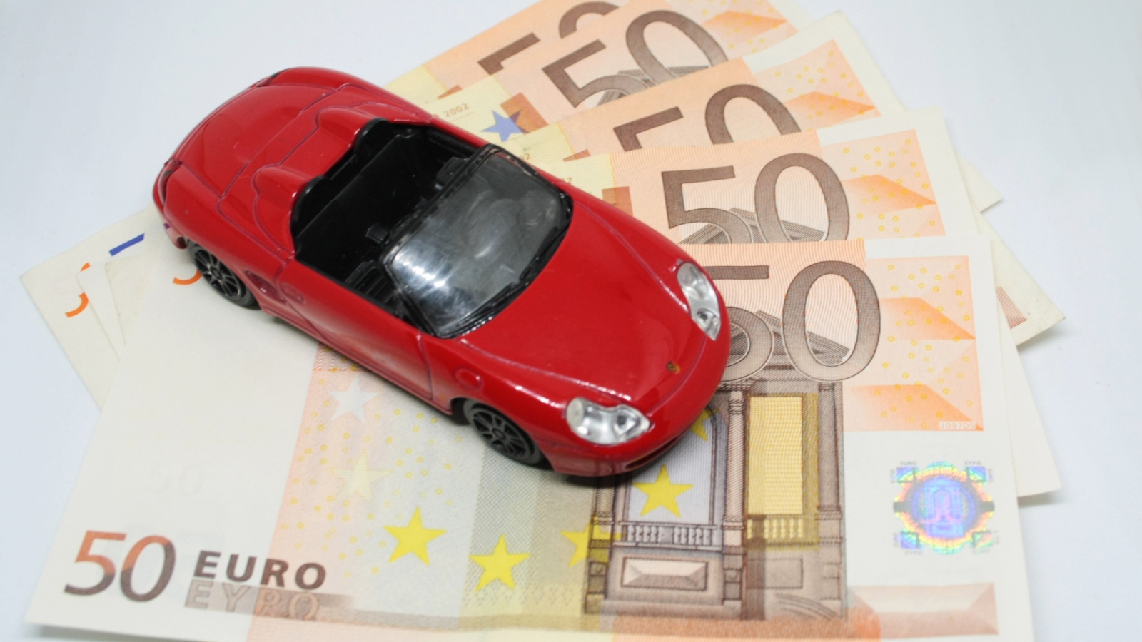 Red toy car with euro bills