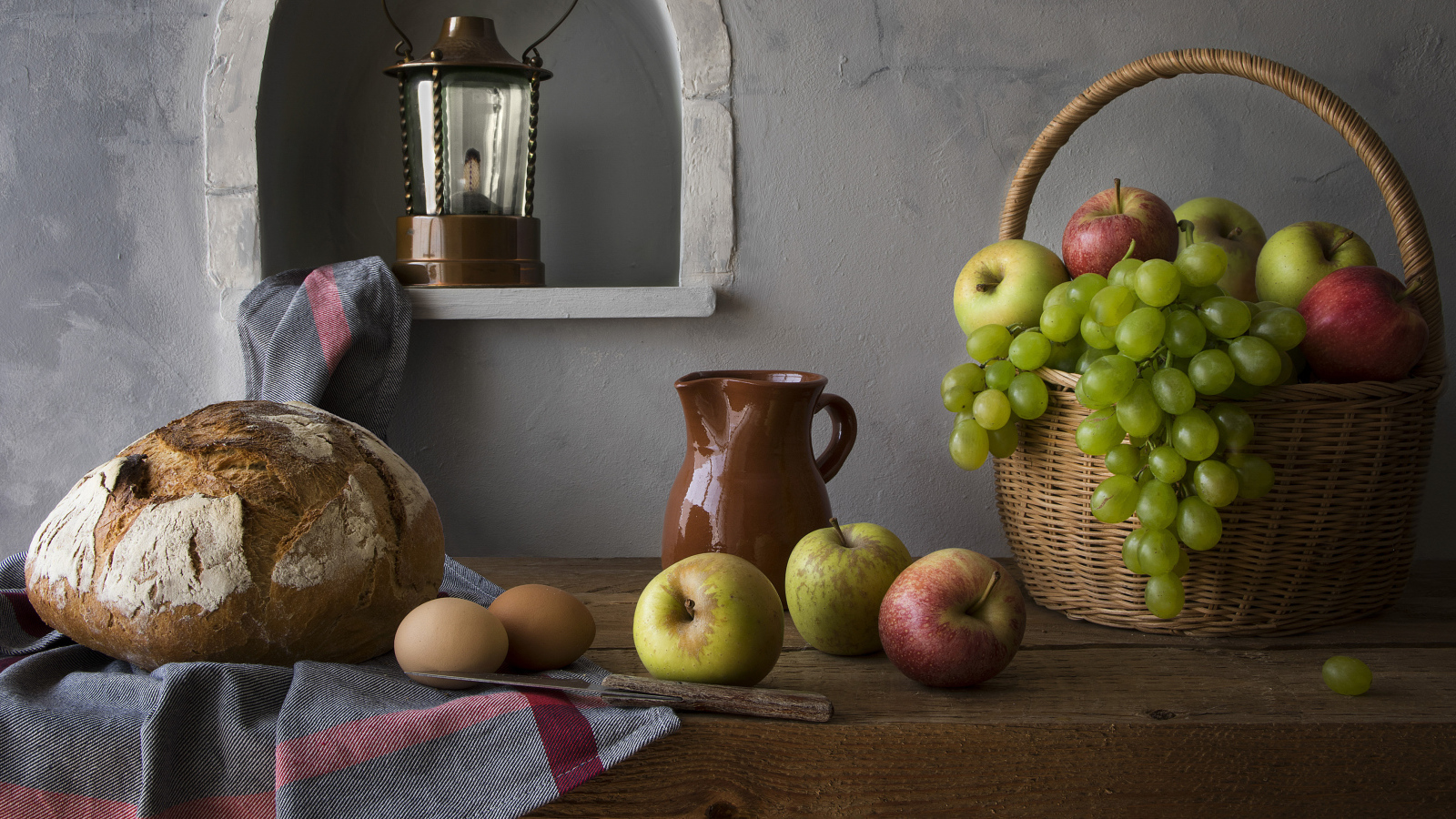 Basket with apples and grapes on a table with bread and eggs
