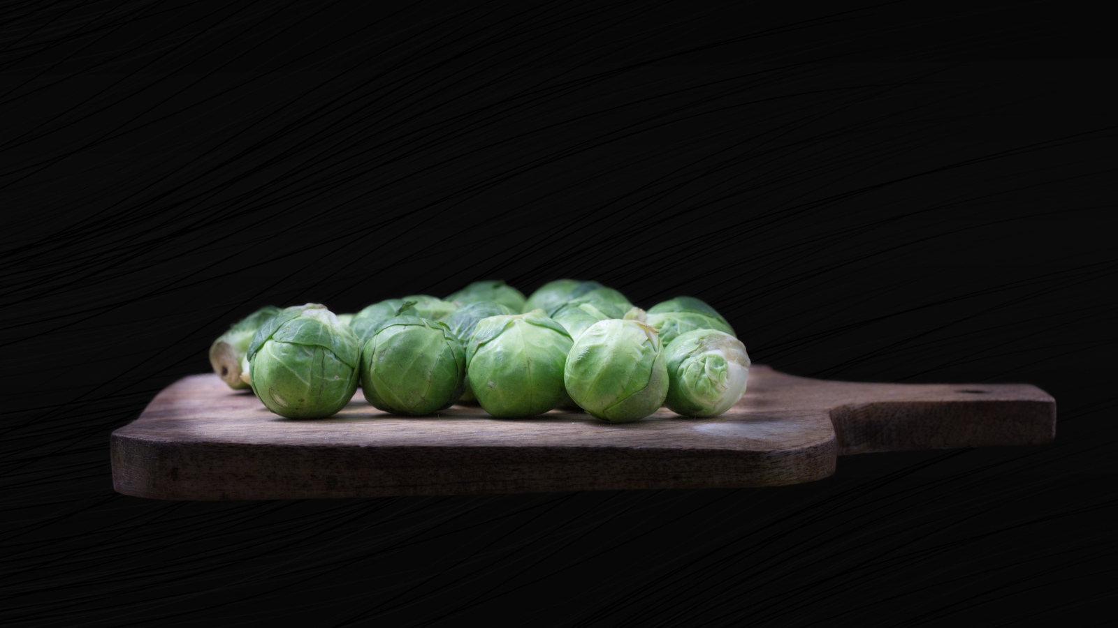 Брюссельская капуста на разделочной доске  на черном фоне