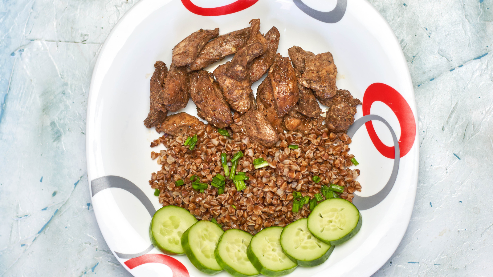 Гречка на тарелке с мясом и огурцами