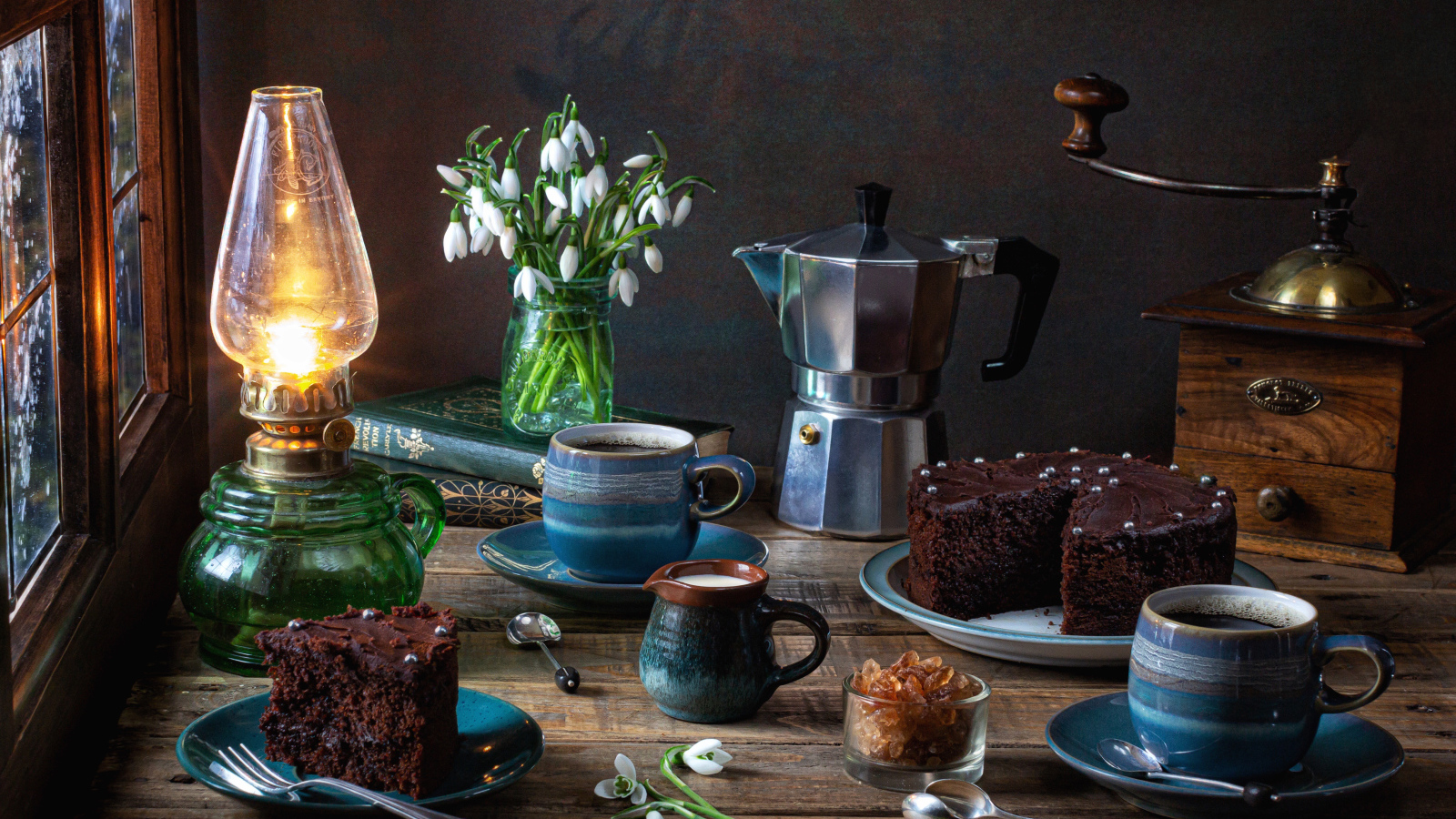 Шоколадный торт на столе с кофе, букетом подснежников и лампой