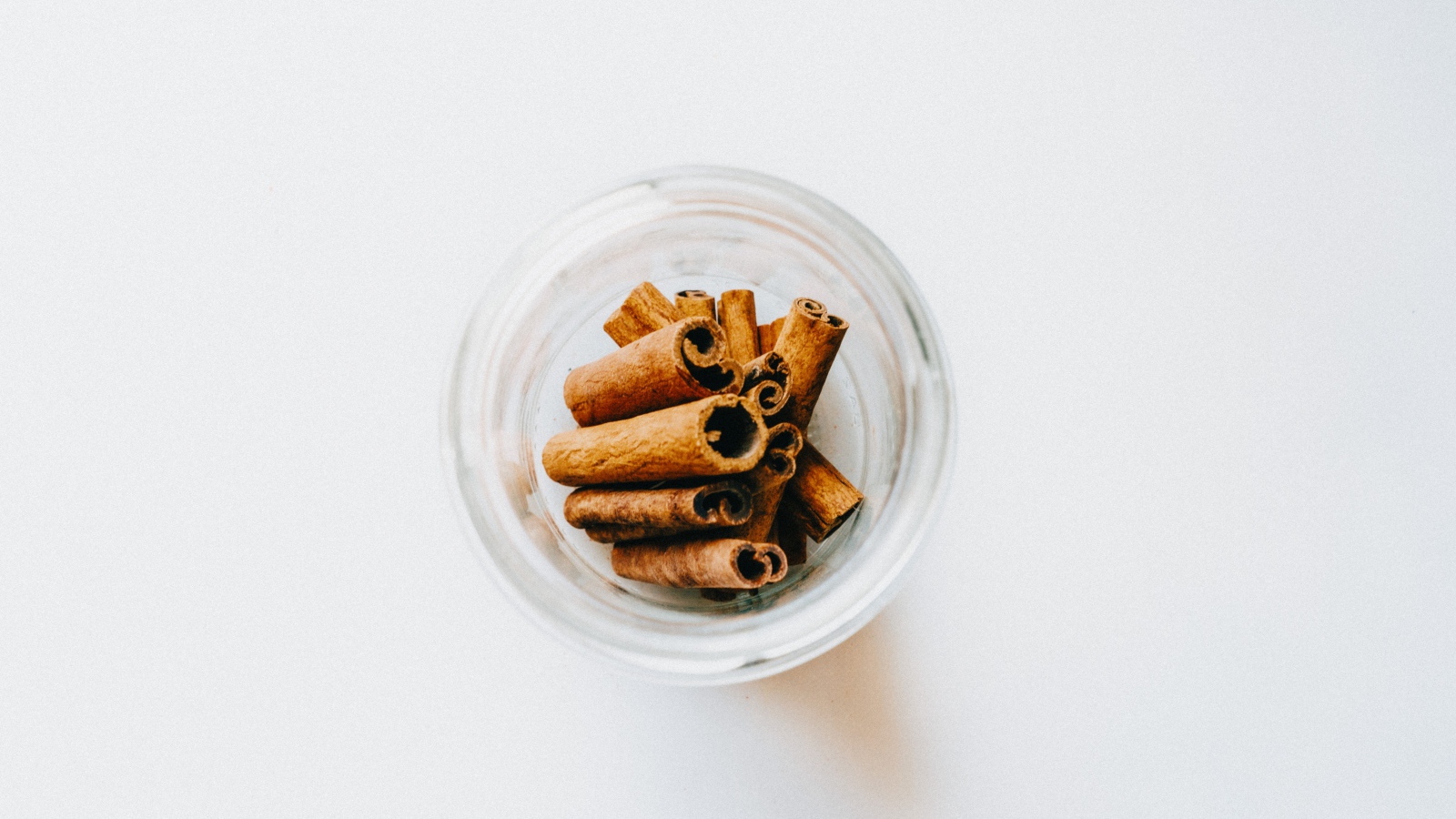 Корица в стеклянной банке на белом фоне 