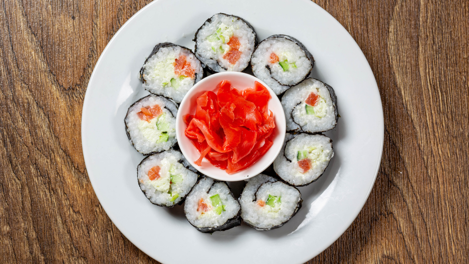 Вкусные суши на большой белой тарелке с имбирем