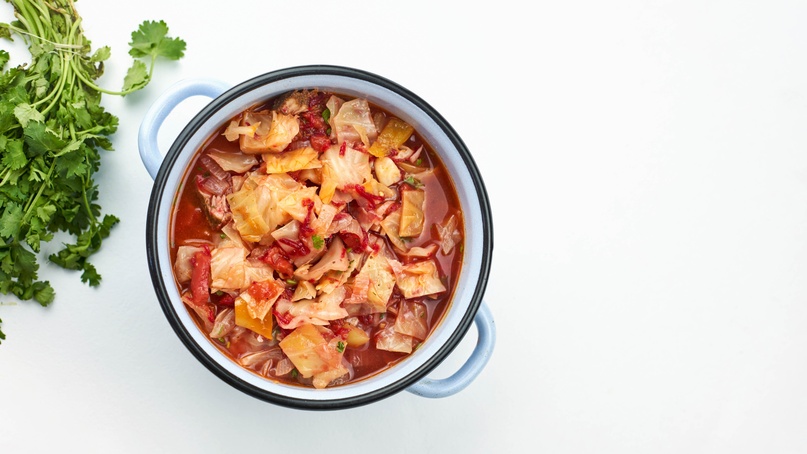 Горячие щи в кастрюле на столе с петрушкой