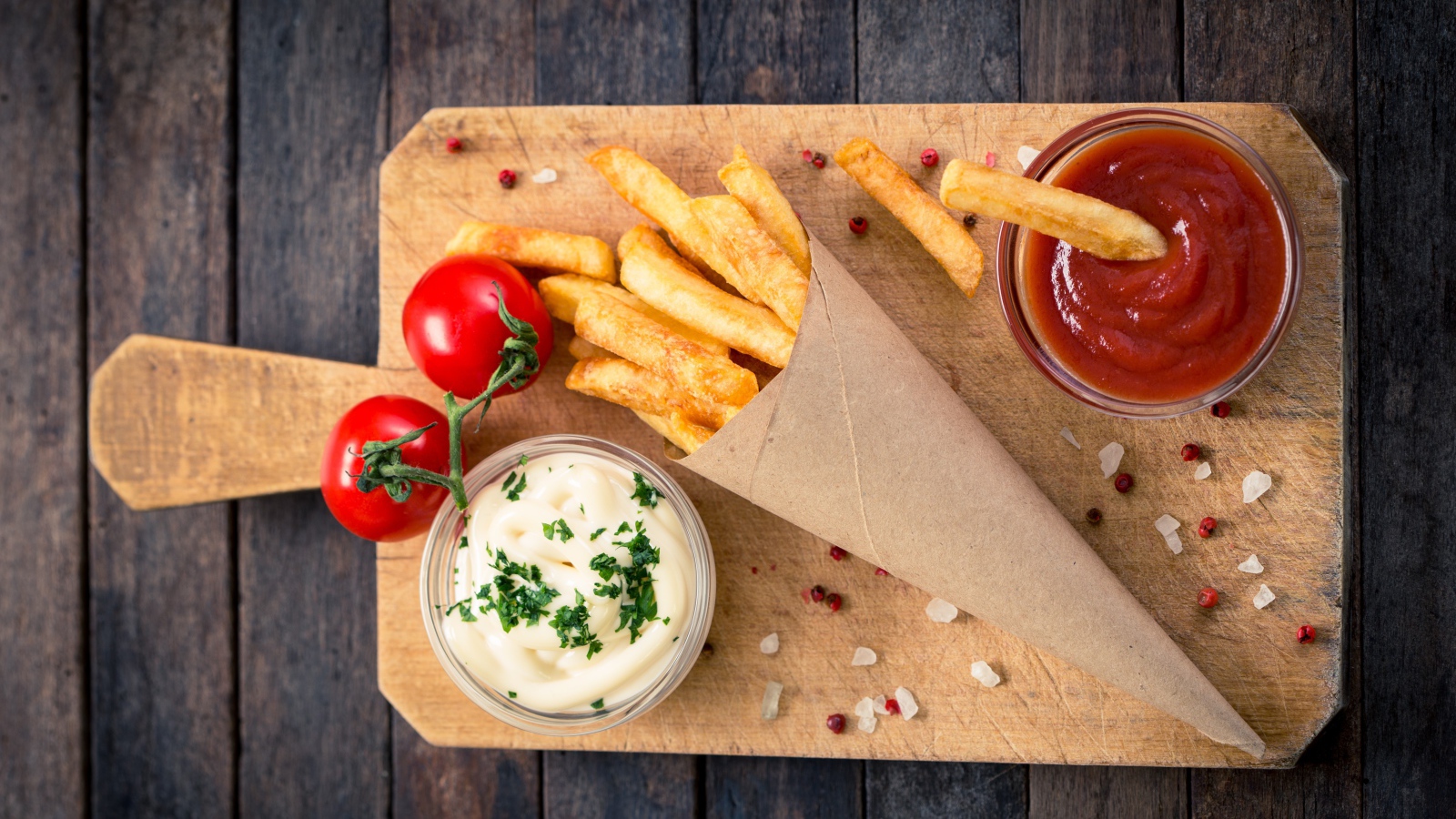 Кетчуп, соус и картофель фри на доске с помидорами