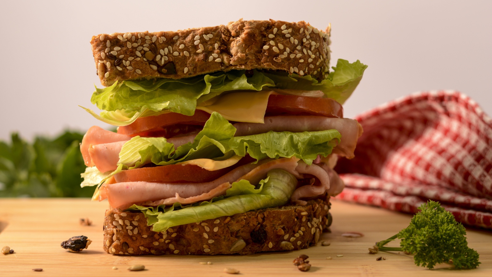 Большой бутерброд с ветчиной, сыром, помидорами и листьями салата 