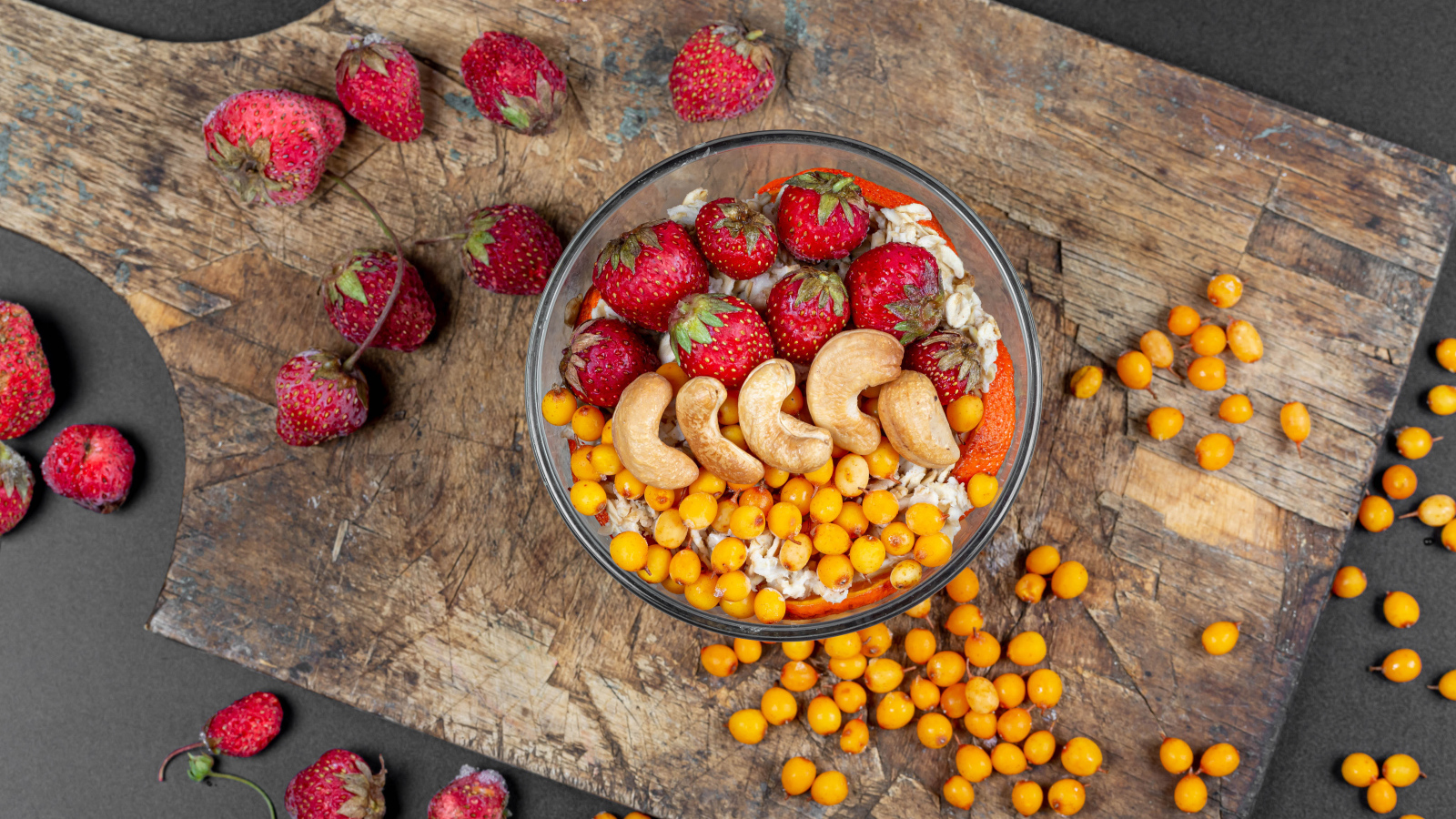 Мюсли с клубникой, орехами и облепихой на доске 