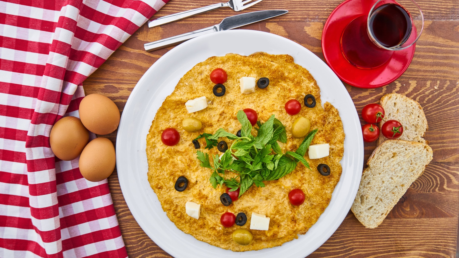 Омлет на столе с чаем, помидорами, яйцами и хлебом