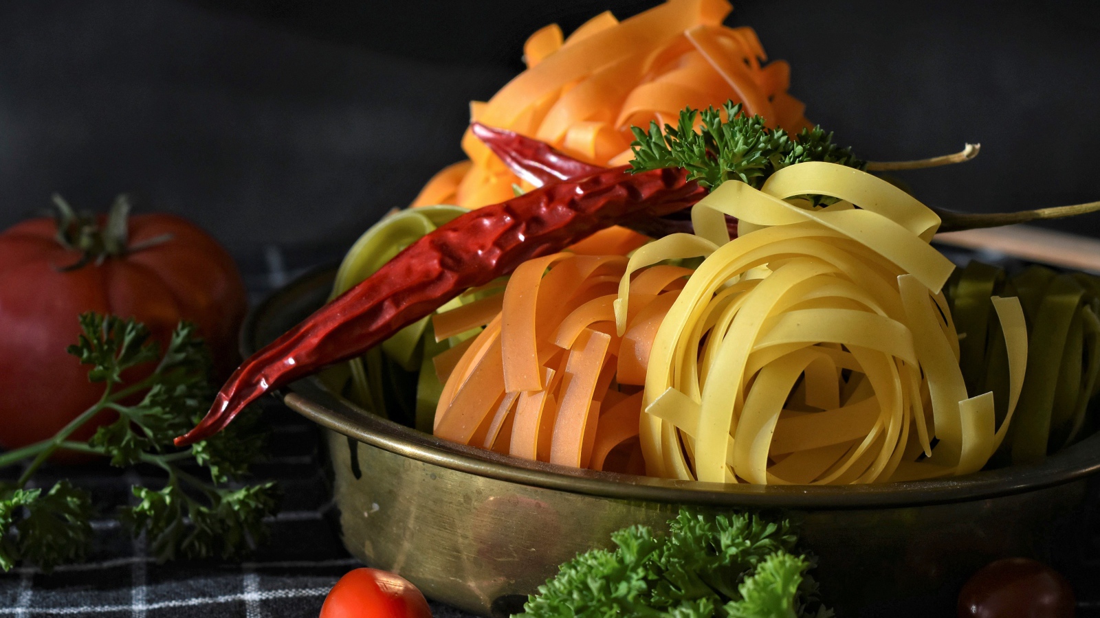 Сырая лапша на столе с острым перцем и петрушкой