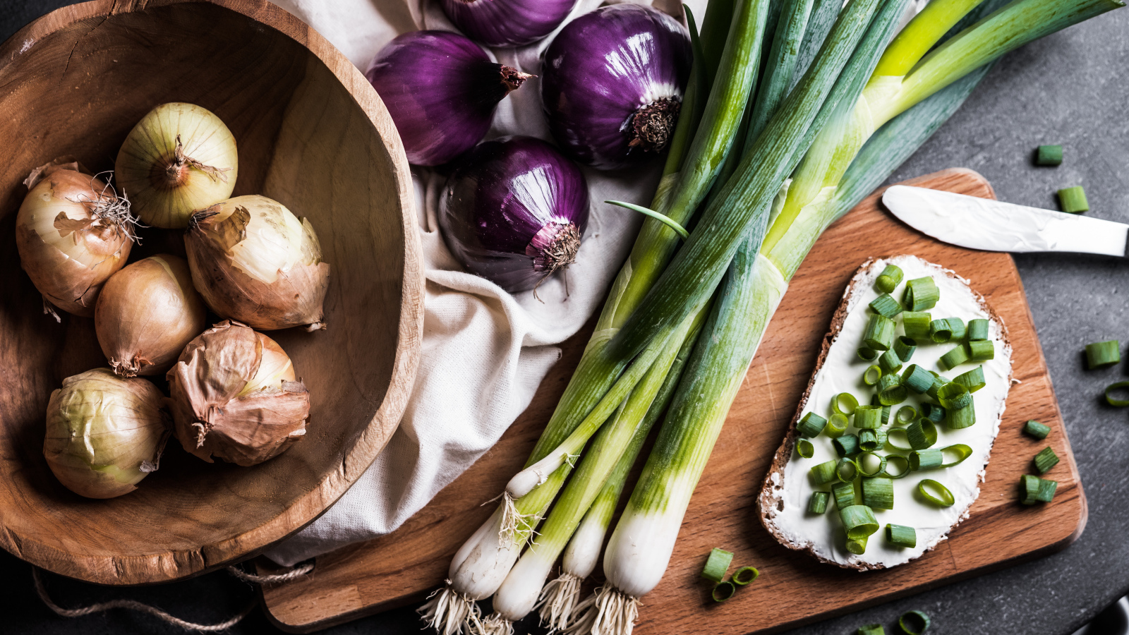 Бутерброд на столе с зеленым и репчатым луком