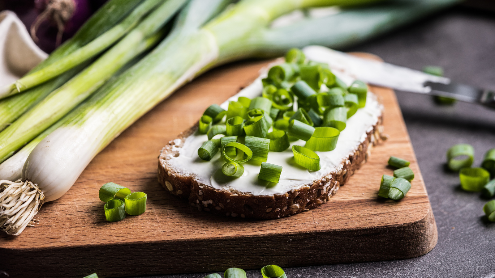 Бутерброд с маслом и зеленым луком на столе 