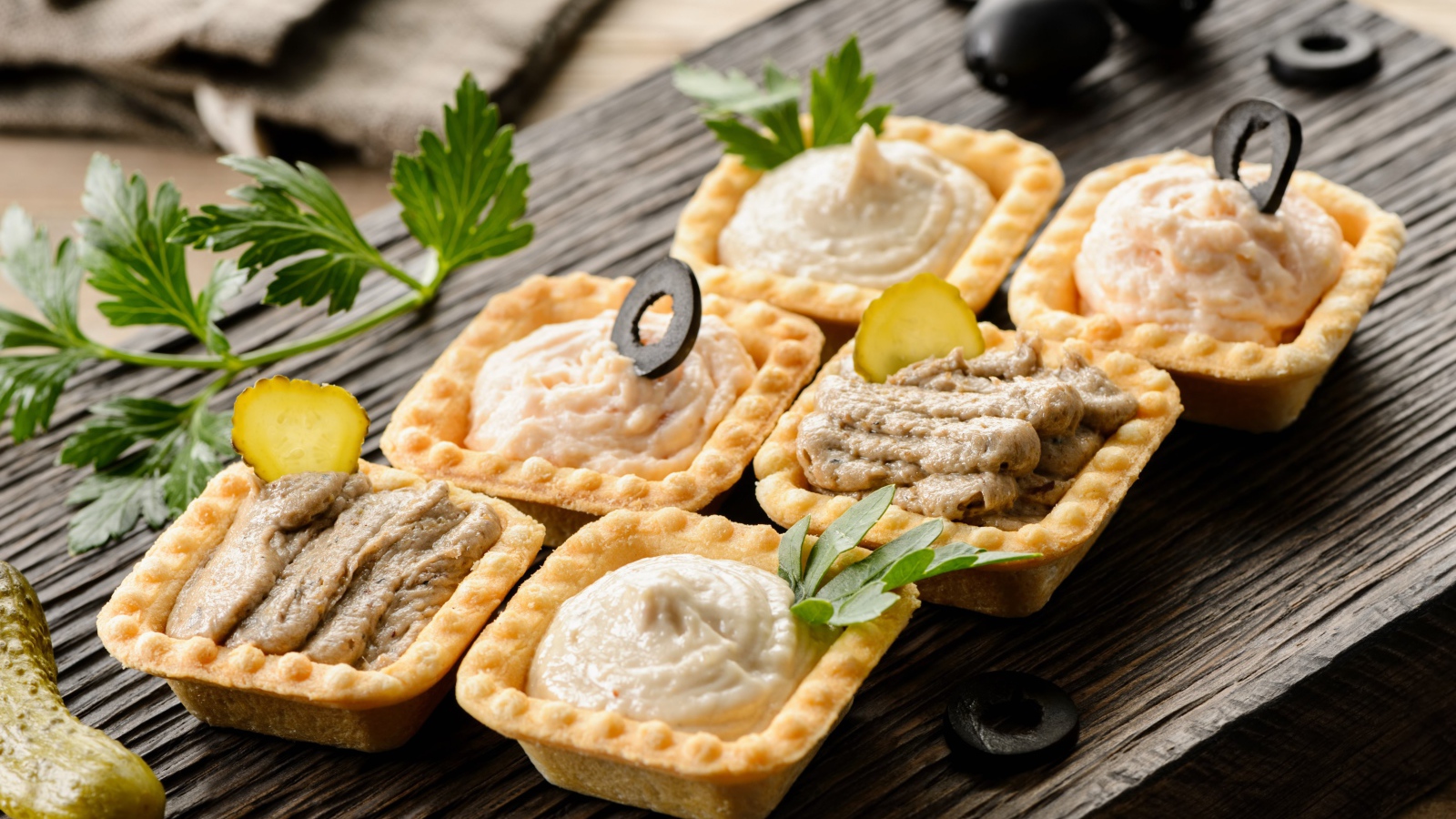 Тарталетки с паштетом на столе с оливками 