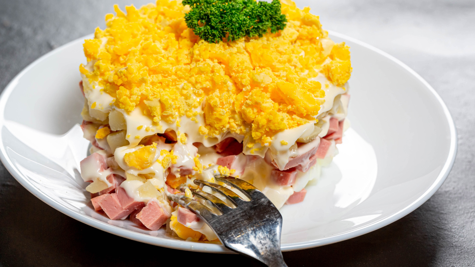 Вкусный салат на белой тарелке с вилкой