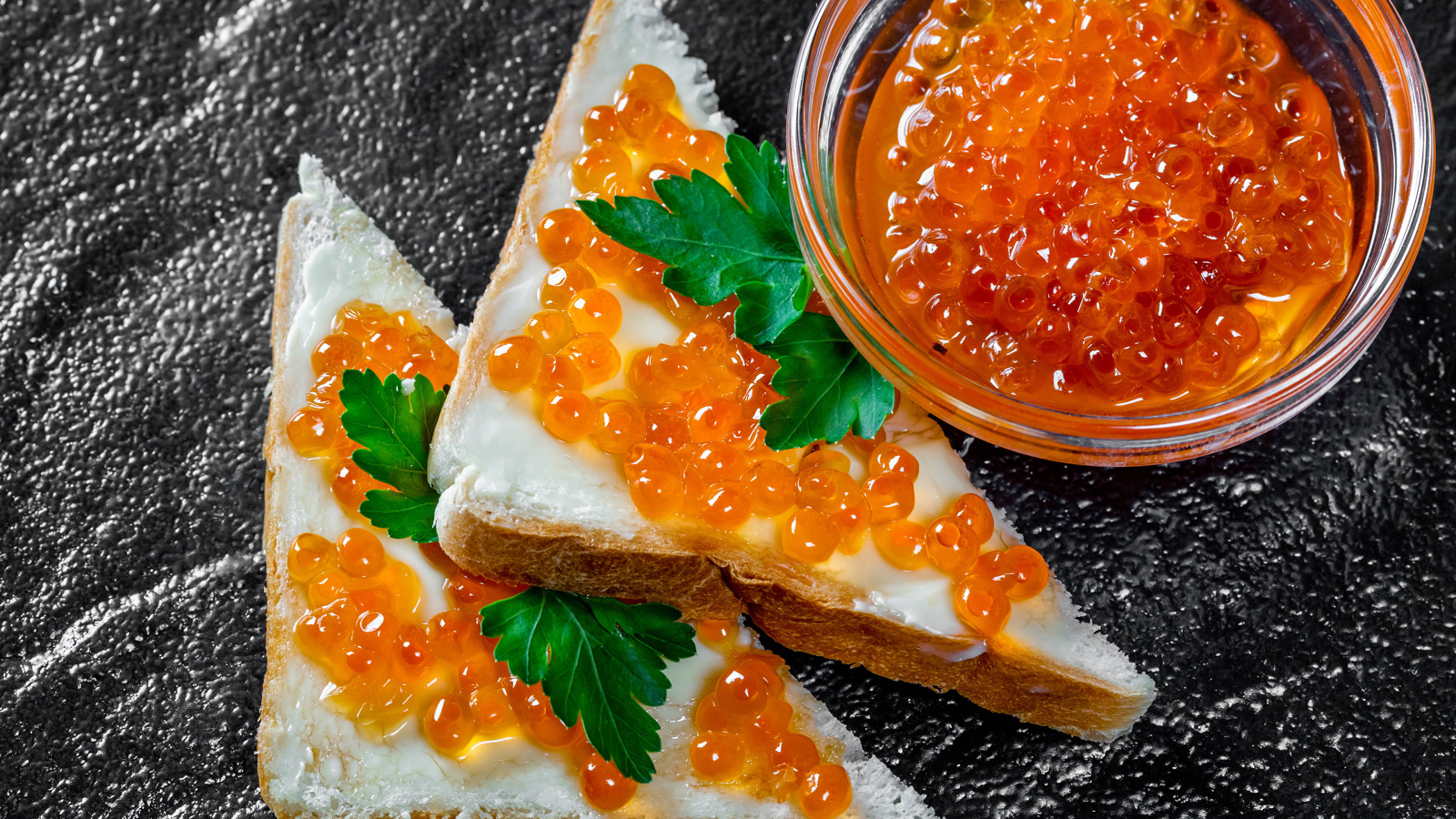 Два бутерброда с красной икрой на столе