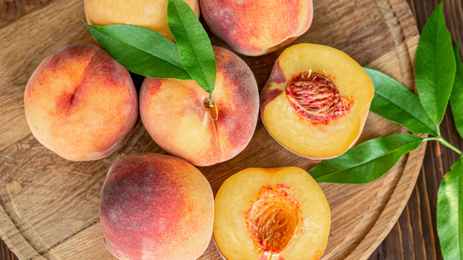 Аппетитные свежие персики на деревянной доске