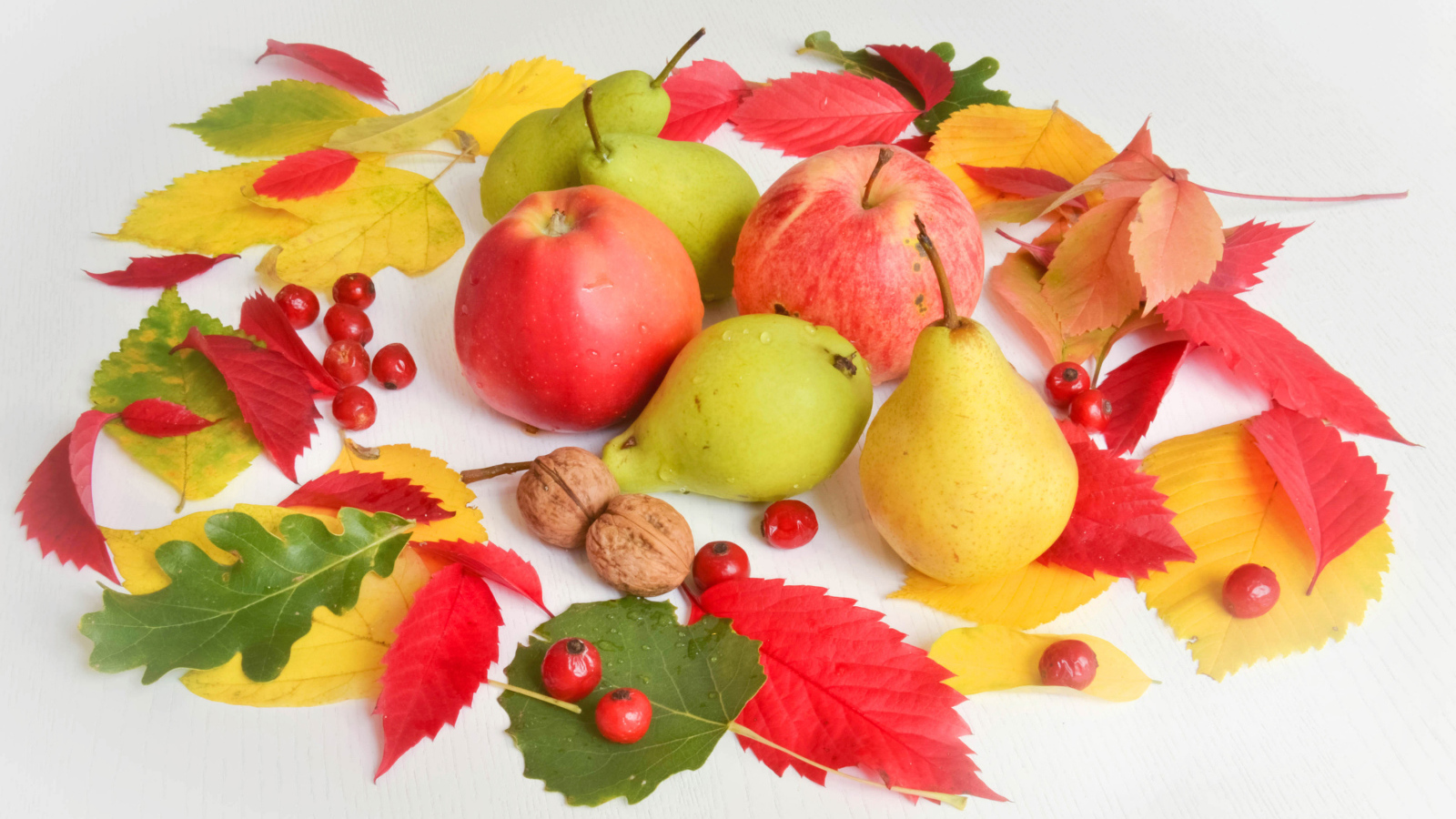 Яблоки и груши с опавшими листьями на белом фоне