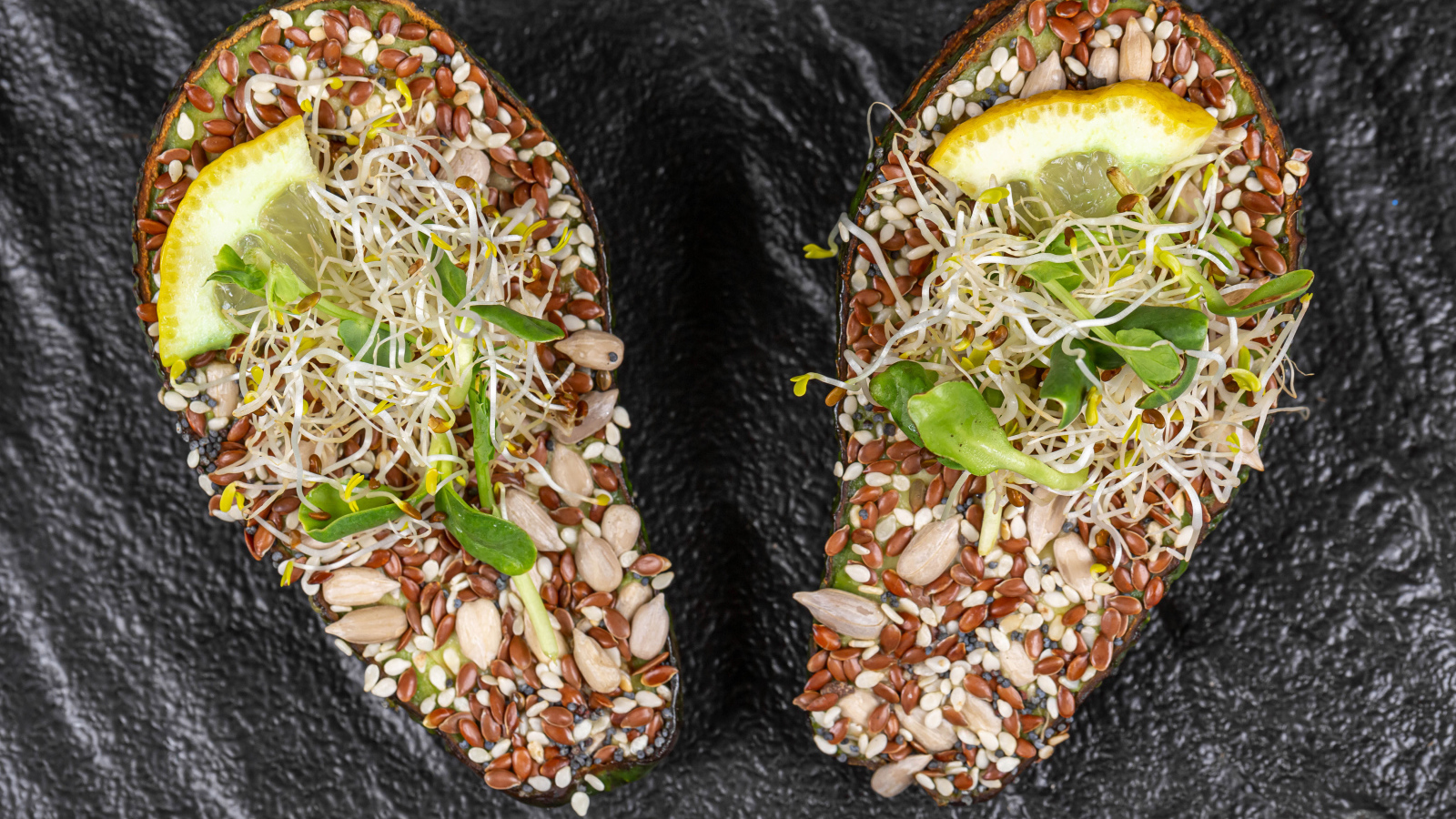 Половинки авокадо с проросшими зернами на столе