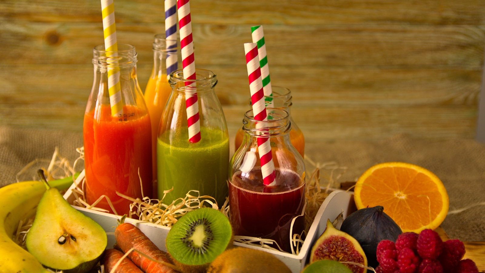 Бутылочки с соком на столе с фруктами 