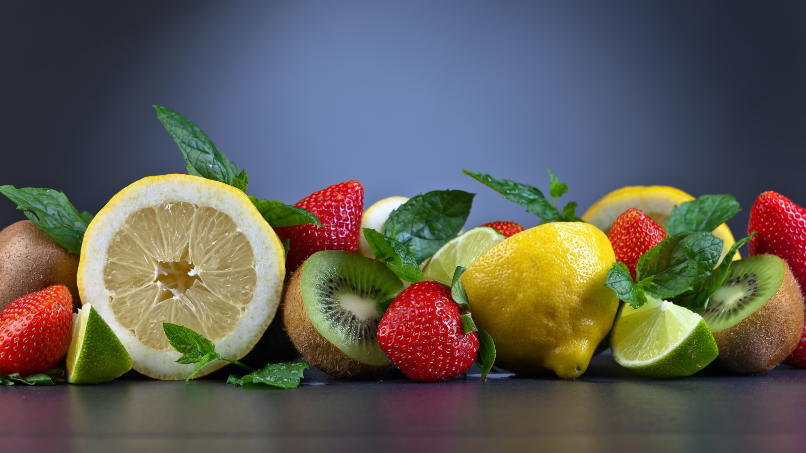 Лимоны на столе с киви и ягодами клубники 