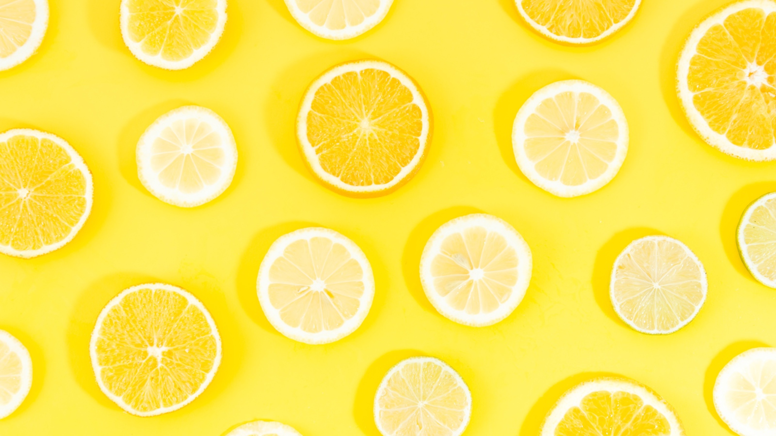 Кружочки апельсина и лимона на желтом фоне