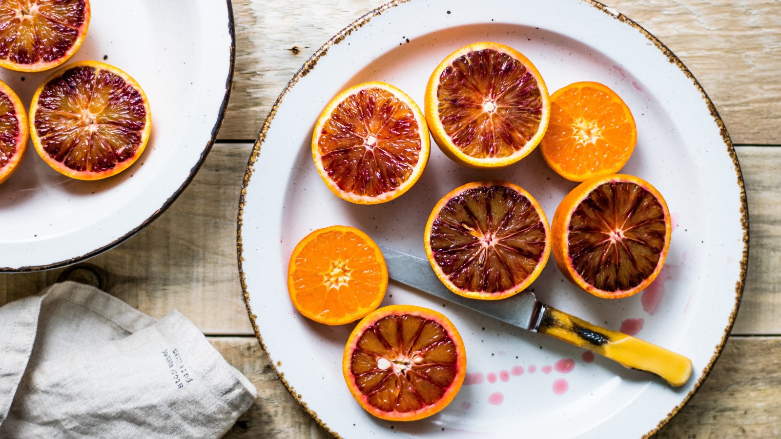 Половинки апельсина на тарелке с ножом