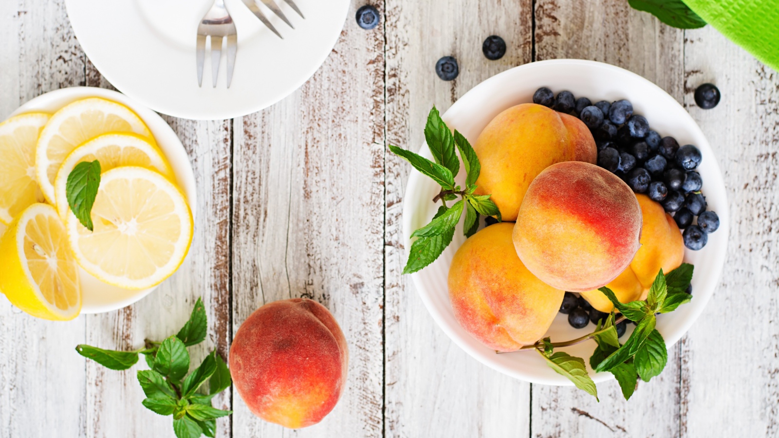 Персики на столе с лимоном и ягодами черники