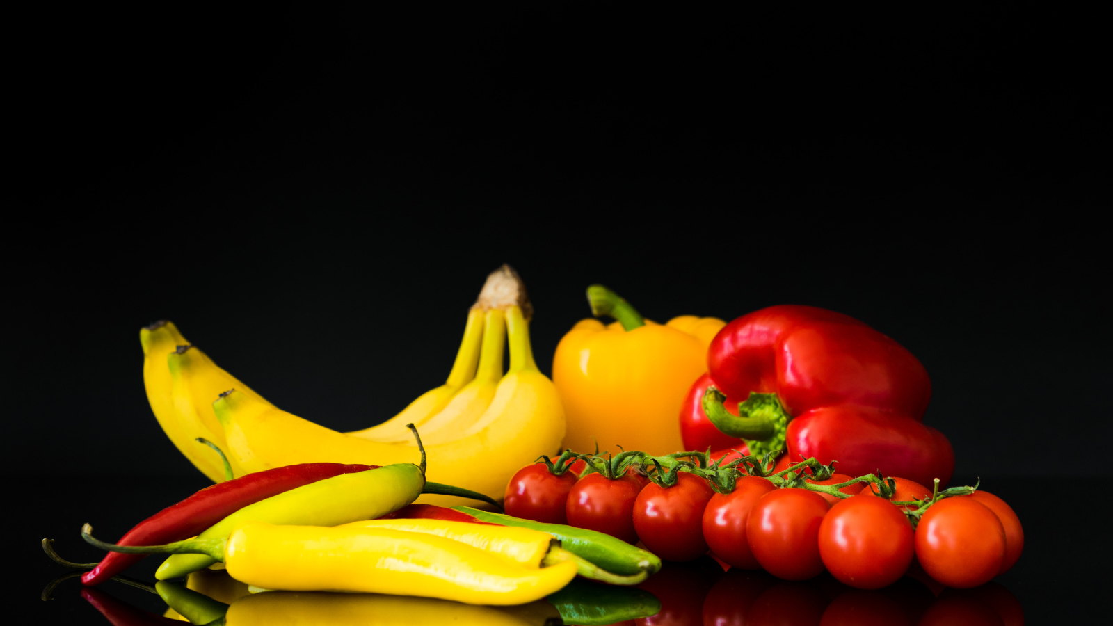 Перец, помидоры и бананы на черном фоне