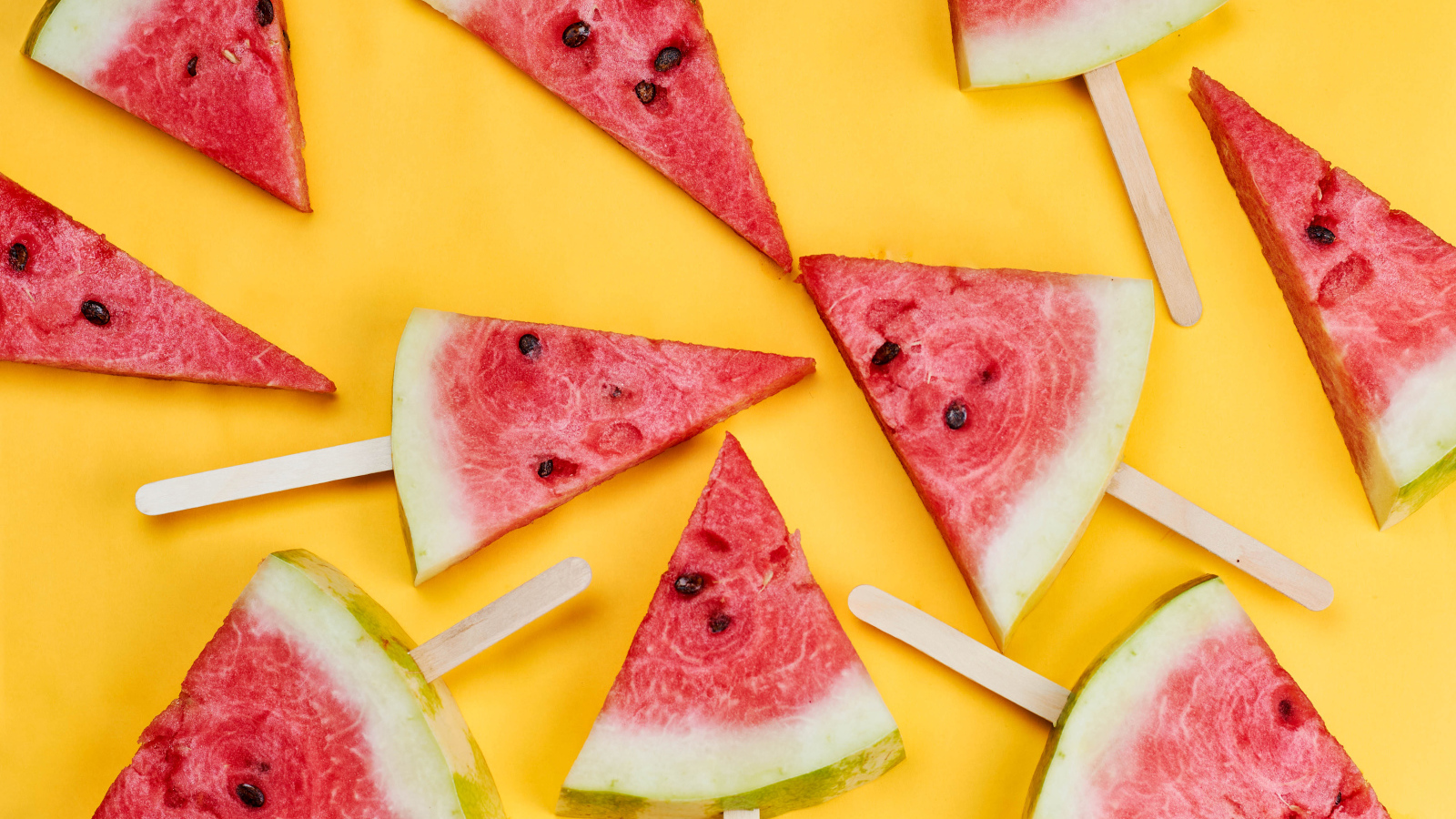 Кусочки арбуза на палочках на желтом фоне