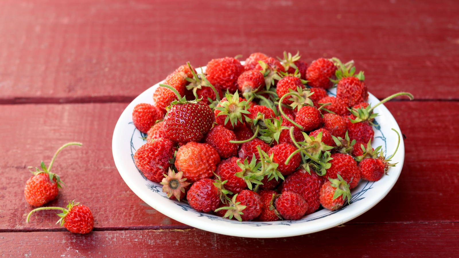 Тарелка со спелой домашней клубникой на столе