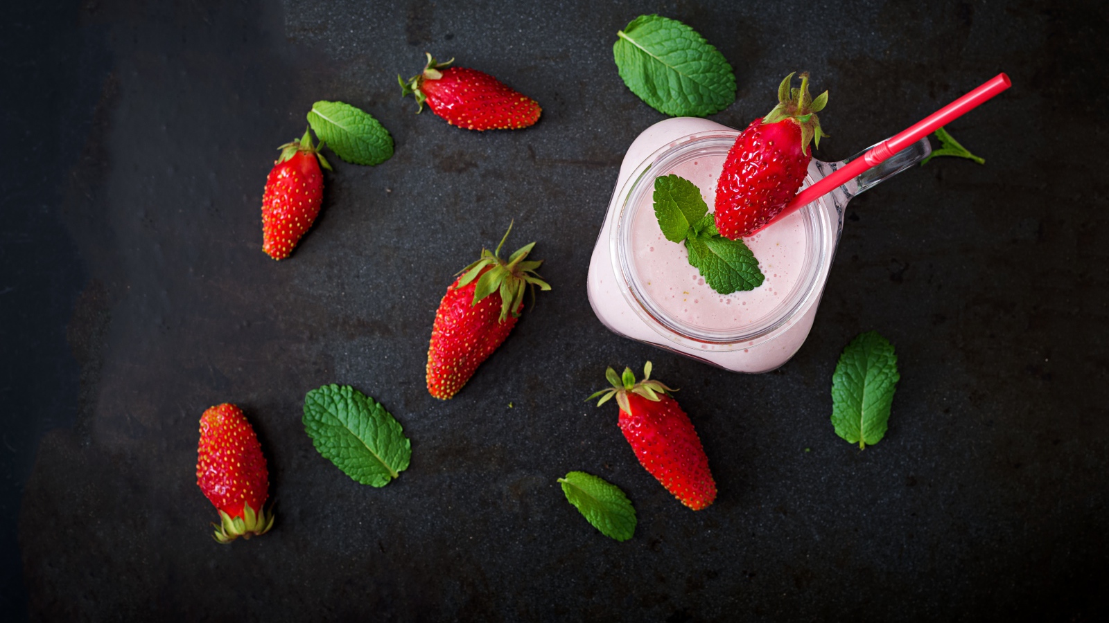 Красная клубника на черном столе с йогуртом