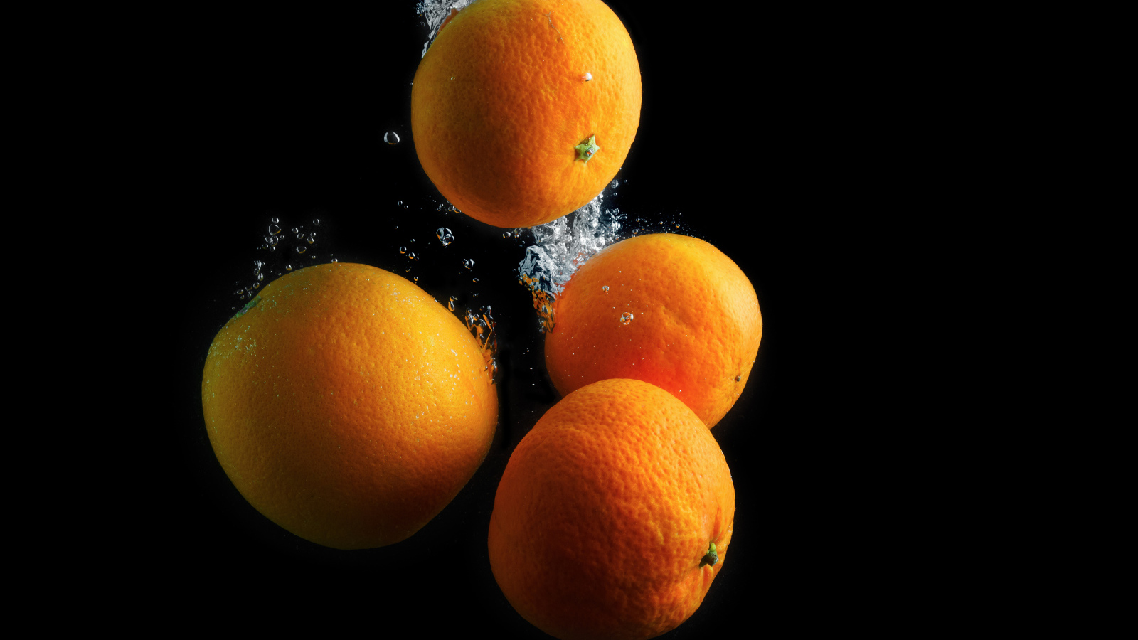 Мандарины и апельсины в воде на черном фоне