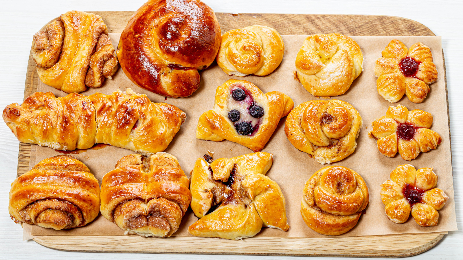 Разная свежая выпечка на доске на белом фоне