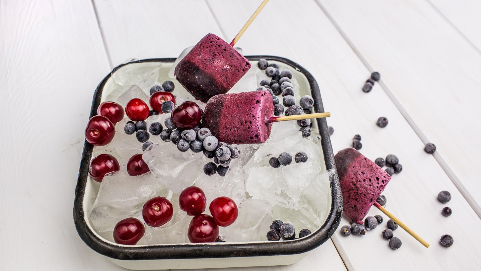 Ягодное мороженое в лотке со льдом, черникой и вишней 