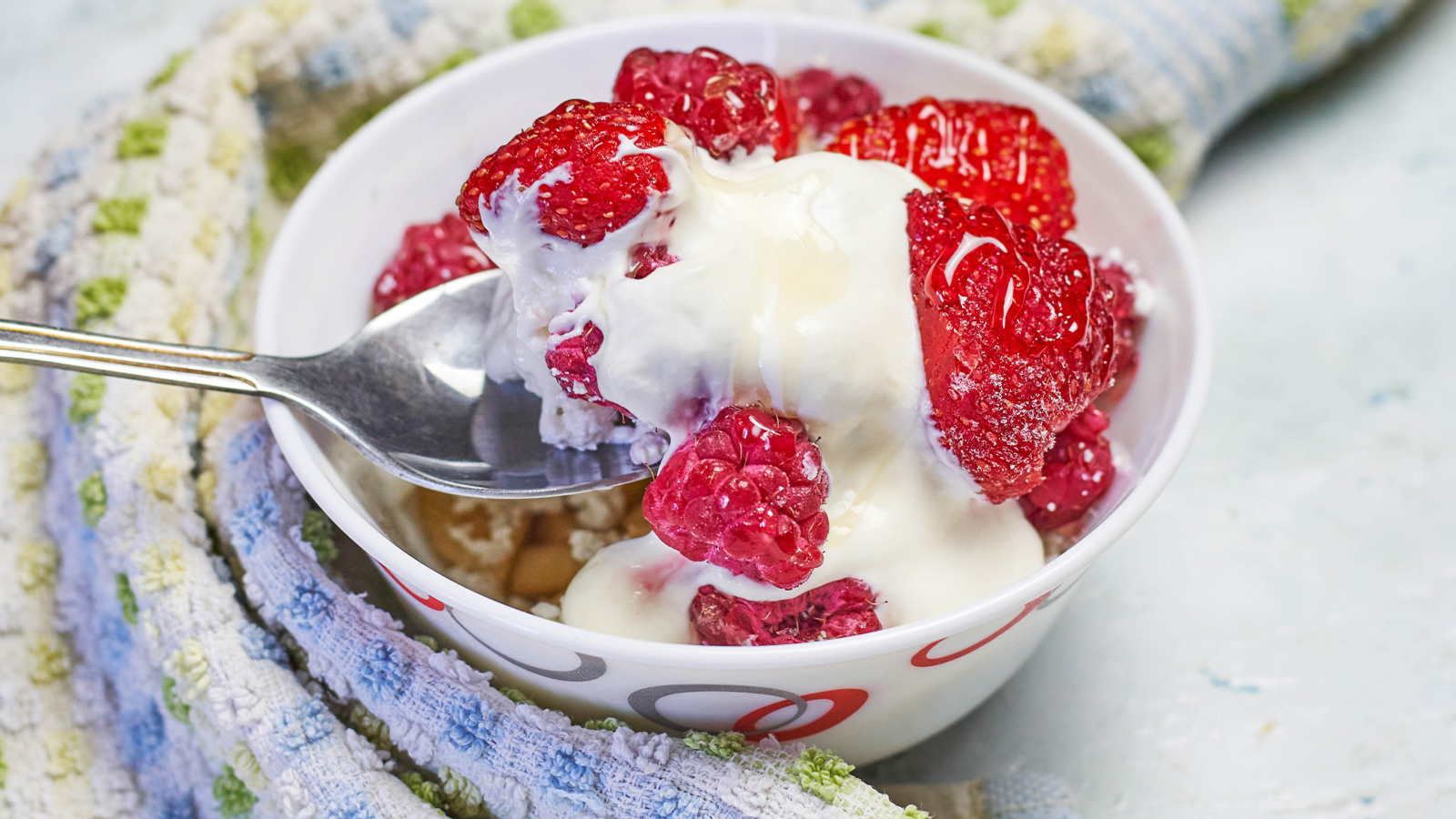 Завтрак с йогуртом и малиной в миске с ложкой