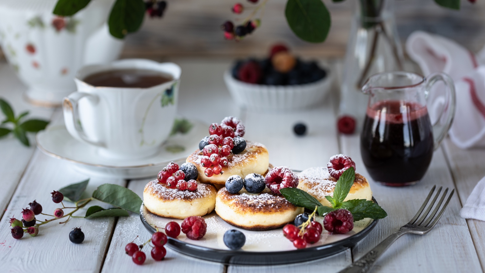 Сырники на столе с ягодами и чаем на завтрак